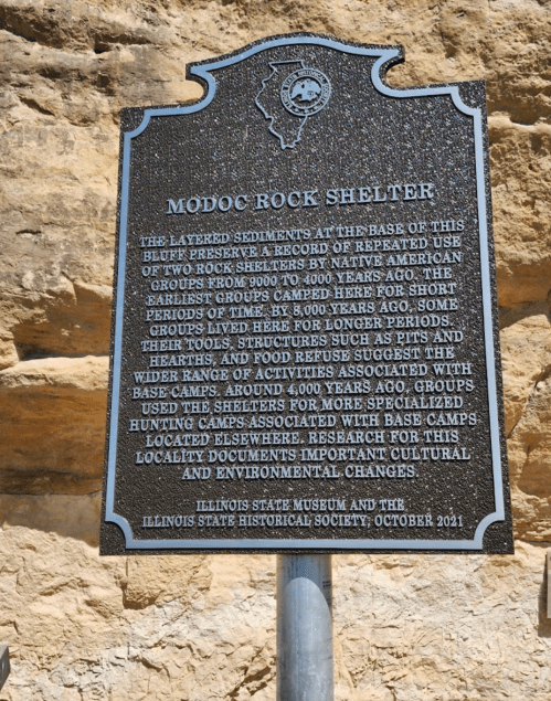 Historical marker about Modoc Rock Shelter, detailing its significance to Native American groups over thousands of years.