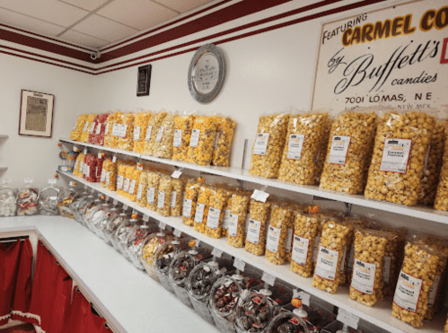 A candy shop interior with shelves filled with colorful bags of popcorn and jars of assorted candies.