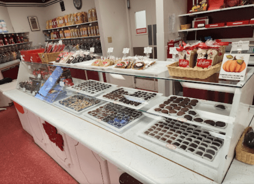 A display case filled with assorted chocolates and candies in a colorful candy shop.