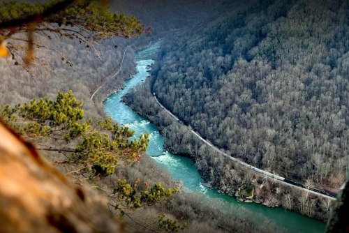 A winding river flows through a mountainous landscape, surrounded by dense trees and rocky terrain.