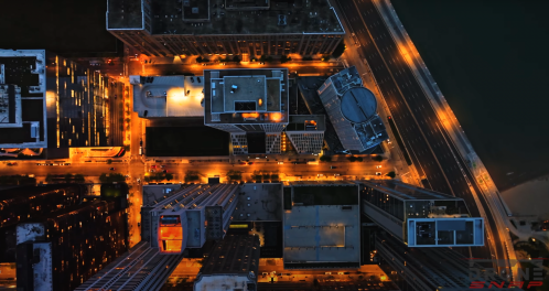 Aerial view of a city at night, showcasing illuminated buildings and streets.