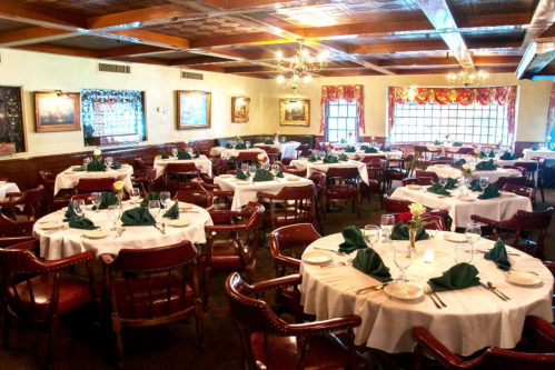 Elegant restaurant interior with neatly set tables, white tablecloths, and decorative floral arrangements.