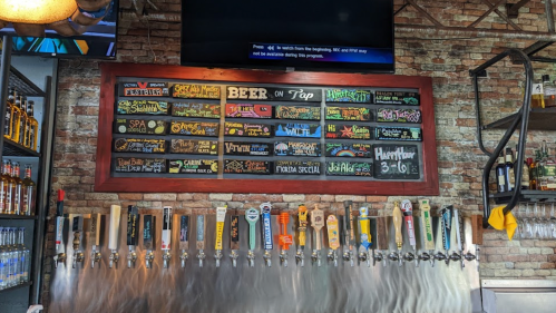 A bar display featuring a chalkboard menu of beers on tap and various tap handles below.