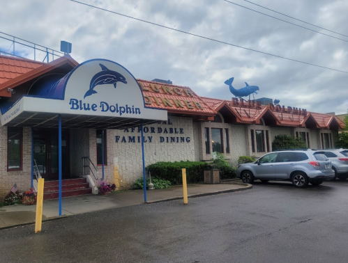 Exterior of the Blue Dolphin restaurant, featuring a blue dolphin sign and a family dining theme, on a cloudy day.