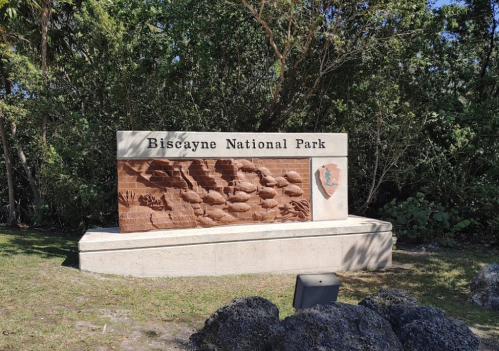 Sign for Biscayne National Park featuring a relief of marine life, surrounded by lush greenery.