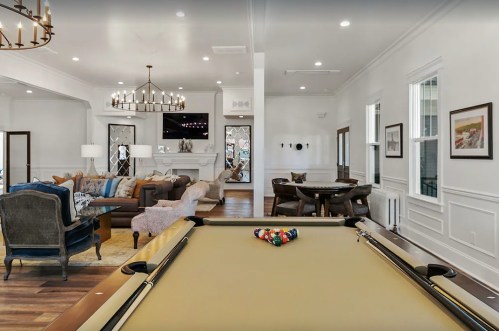 A spacious living area featuring a pool table, cozy seating, and elegant decor in a well-lit room.