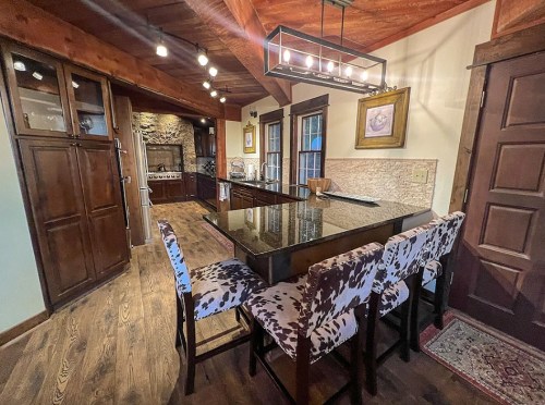 A cozy kitchen featuring dark wood cabinets, a large island with seating, and rustic decor elements.