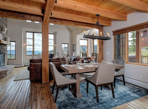A modern dining area with a wooden table, chairs, and large windows showcasing a scenic view.