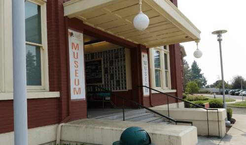 Entrance of a museum with large "MUSEUM" signs, featuring a ramp and decorative light fixtures.