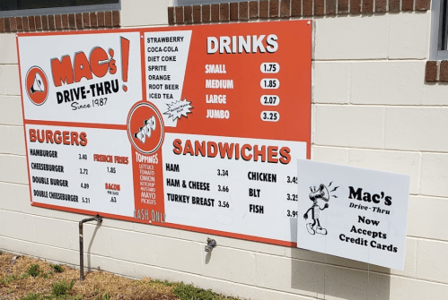 Menu board for Mac's Drive-Thru featuring burgers, sandwiches, and drinks with prices. Now accepts credit cards.