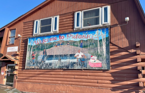 Mural on a wooden building reading "Welcome to Pulaski," depicting people by a stone structure and trees in the background.
