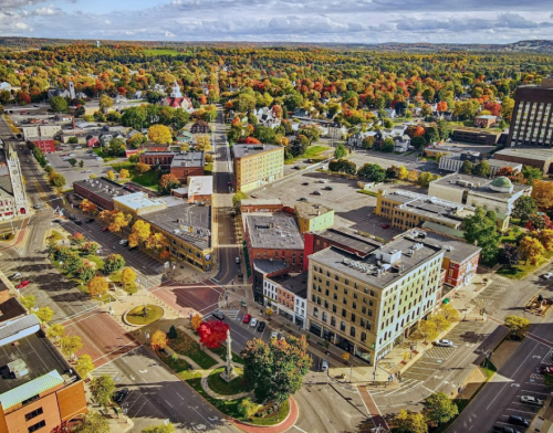 Aerial view of a vibrant town with colorful autumn trees, intersecting streets, and historic buildings.