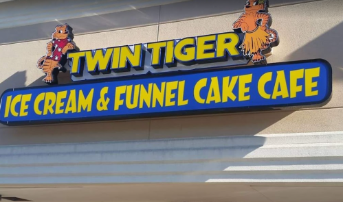 Sign for "Twin Tiger Ice Cream & Funnel Cake Cafe" featuring colorful lettering and cartoon tiger mascots.