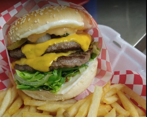 A juicy cheeseburger with two patties, lettuce, and cheese, served with a side of golden French fries.