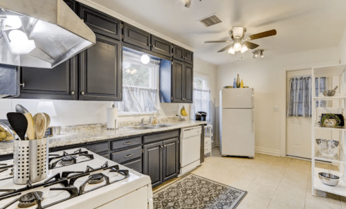 Modern kitchen with dark cabinets, granite countertops, a white refrigerator, and a gas stove, featuring a cozy layout.