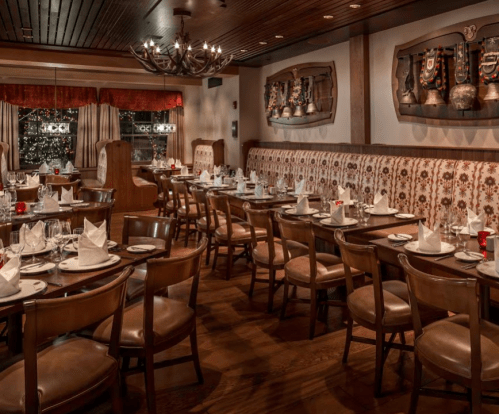 Cozy restaurant interior with wooden tables, chairs, and festive decor, featuring a warm, inviting atmosphere.