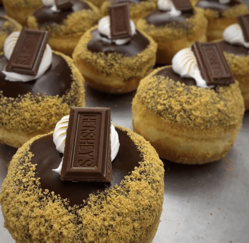 Delicious donuts topped with chocolate, whipped cream, and Hershey's chocolate bars, sprinkled with graham cracker crumbs.