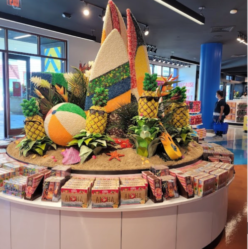 Colorful display of surfboards, pineapples, and beach items in a store, surrounded by books and decor.