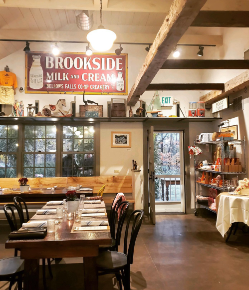 Cozy interior of a café with wooden beams, a vintage milk sign, and a dining area set for guests.