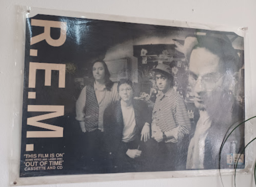 Black and white poster of the band R.E.M., featuring four members with the text "This film is on" and album details.