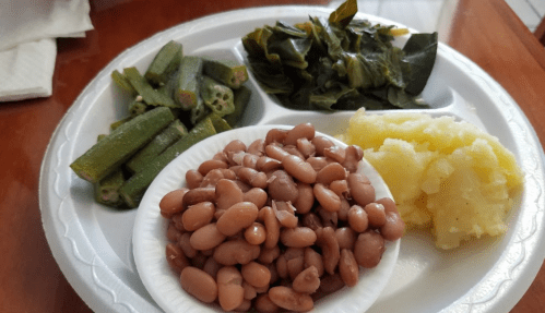 A plate with okra, collard greens, mashed potatoes, and a serving of pinto beans.