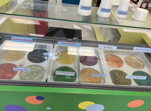 A colorful ice cream display with various flavors labeled, including Chocolate Brownie, Red Velvet, and Orange Creamsicle.