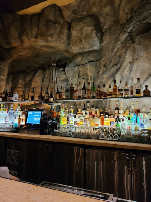 A well-stocked bar with various bottles of liquor displayed against a rocky backdrop.