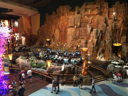A vibrant indoor space featuring a rocky landscape, a bar area, and people enjoying the atmosphere.