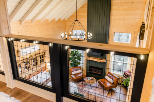 A cozy, modern cabin interior with a view of a living area featuring leather chairs and a fireplace.