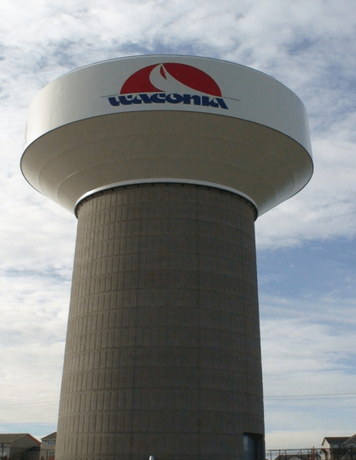 Water tower with a circular top and the logo "LAVCONIA" against a cloudy sky.