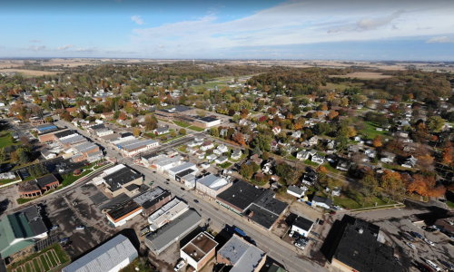Aerial view of a small town with residential areas, commercial buildings, and autumn foliage in the landscape.