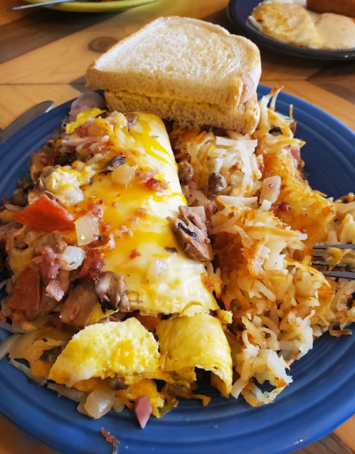 A blue plate with a cheesy omelette, hash browns, and a slice of toasted bread.