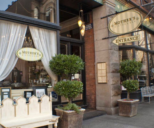 Exterior of Mother's Bistro, featuring a welcoming entrance with potted plants and a cozy seating area.