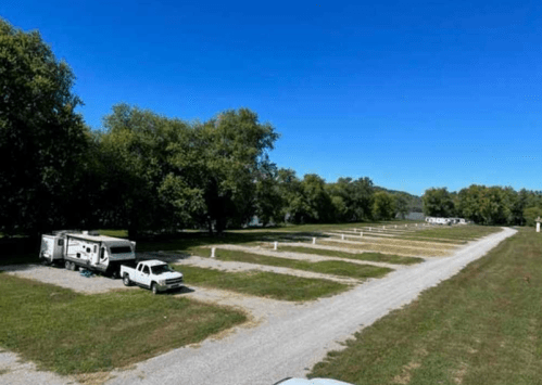 A spacious RV park with several empty spots, surrounded by trees and a clear blue sky.