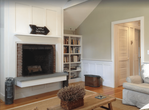 Cozy living room with a fireplace, bookshelves, and a light-colored sofa, featuring a rustic decor style.