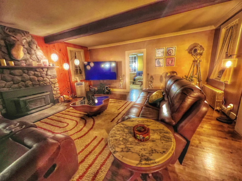 Cozy living room with a stone fireplace, leather sofas, a coffee table, and warm lighting.