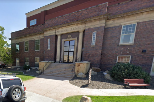 Exterior view of a brick building labeled "Masonic Temple," featuring steps, windows, and landscaped grounds.