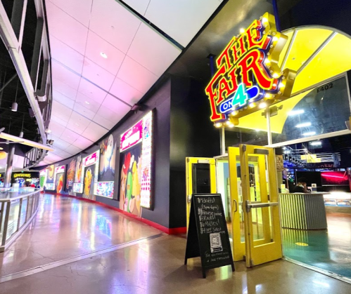 Entrance to "The Fair on 4," featuring bright signage and colorful wall displays in a modern indoor space.