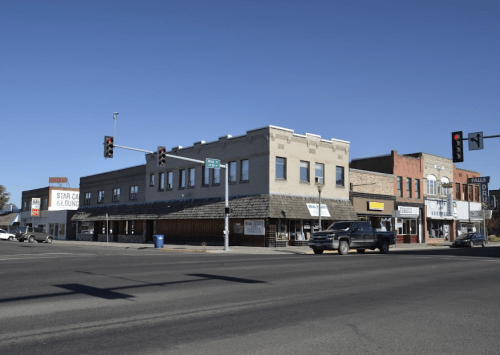 A street view of a small town with shops, traffic lights, and clear blue skies.