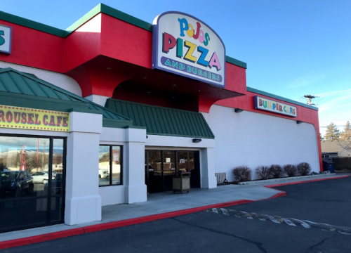 Exterior of PJs Pizza and Burgers, featuring a colorful sign and a green awning, with a parking lot in front.