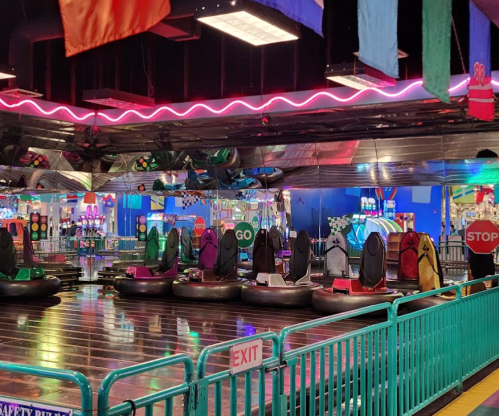 Colorful bumper cars in an amusement park, with vibrant lights and signs indicating "GO" and "STOP."