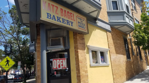 A bakery storefront with a sign reading "Katz Bagel Bakery" and an "OPEN" sign in the window.