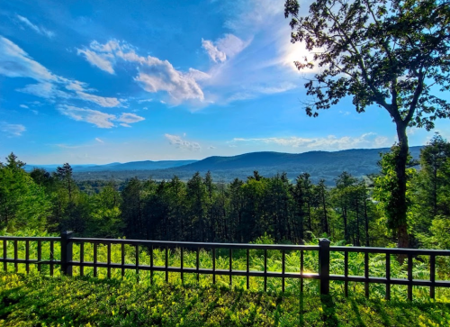 A scenic view of rolling hills and lush greenery under a bright blue sky with scattered clouds.
