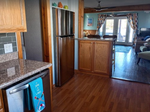 A bright kitchen with wooden cabinets, stainless steel appliances, and an open layout leading to a living area.