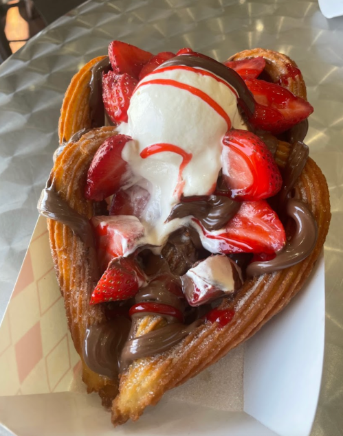 A heart-shaped churro topped with strawberries, chocolate sauce, and a scoop of vanilla ice cream.