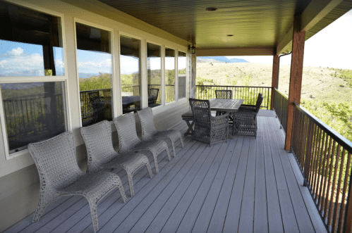 A spacious porch with a wooden table and chairs, overlooking a scenic landscape.