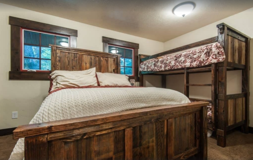 Cozy bedroom featuring a wooden bed and a bunk bed, with warm lighting and rustic decor.