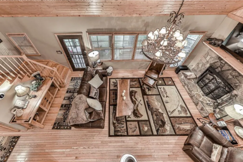 Cozy cabin living room with wooden floors, a stone fireplace, and rustic furniture, viewed from above.