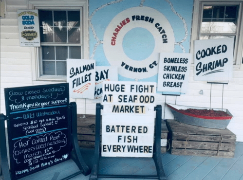 Signage outside Charlie's Fresh Catch in Vernon, CT, advertising seafood specials and a humorous note about a "huge fight."