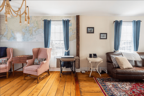 Cozy living room with wooden floors, a map on the wall, and a mix of vintage and modern furniture.